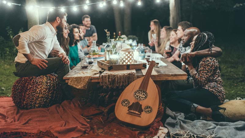 Friends gathered around a long table outdoors under string lights
