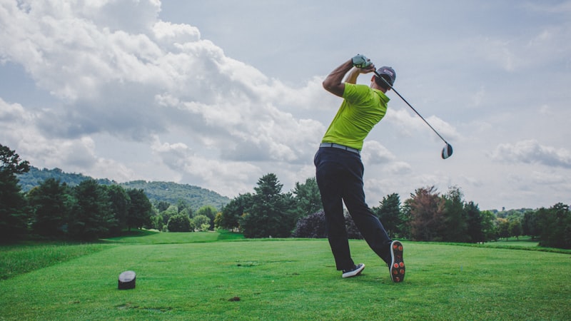 A golfer mid-swing on a bright green fairway