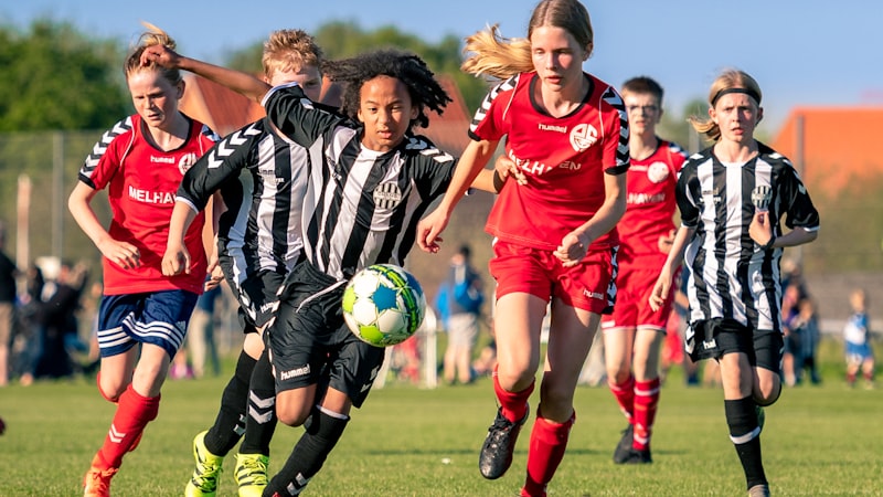 Children playing a soccer match on a grass field