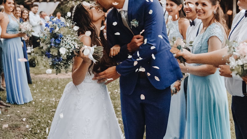 A couple kissing under confetti, surrounded by their wedding party